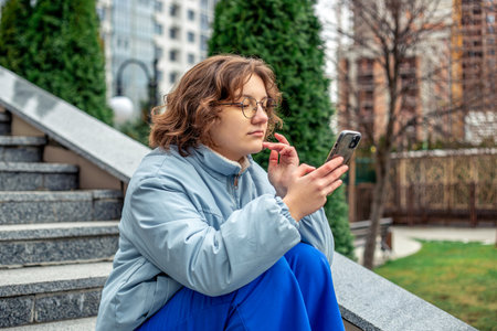 A teenage girl uses a phone in the city. Girl in the city. Technology concept.の写真素材