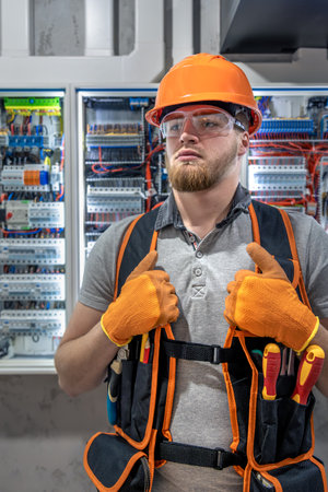 Electrician man in overalls works in the switchboard. Portrait of an electrician in overalls.の写真素材