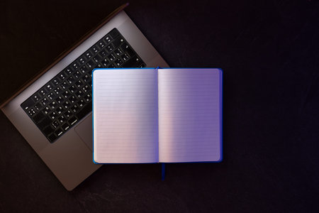 Laptop with blank notepad on black background. Online learning concept.