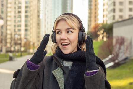 Beautiful young woman listens to music in headphones and walks around the city.の写真素材