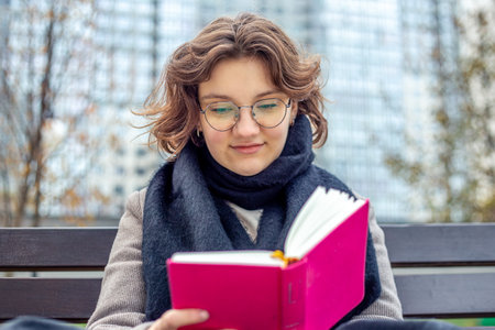 Girl reading a book on the street close-up. Teenage girl reading a book.の写真素材