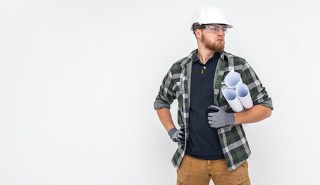 Male builder. Engineer in overalls and helmet holds blueprints and projects in his hands.の写真素材