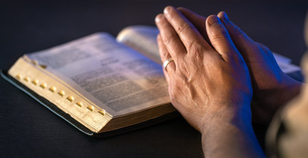 Hands on the Holy Bible. Prayer. Open Bible close-up. Religion concept.の写真素材