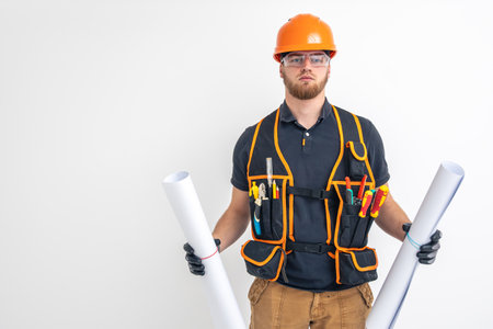 Male builder. Electrical engineer in overalls and helmet holds blueprints and projects in hands.の写真素材