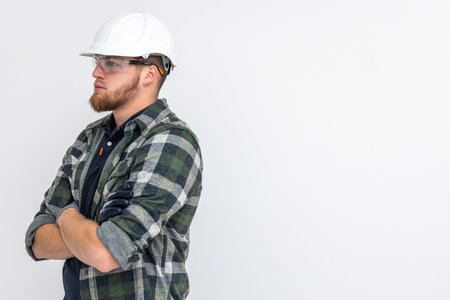 Portrait of a male builder. Engineer in overalls and helmet on a light background.