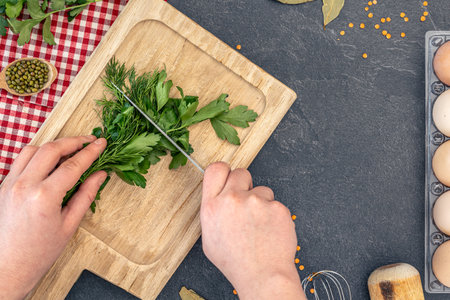 Female hands cutting parsley with dill on a wooden cutting board. Cooking ingredients.の写真素材