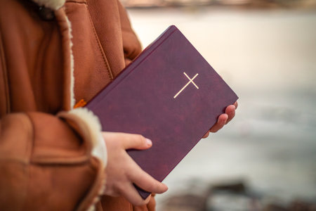 A woman holds the Bible in her hands in nature. Christianity concept.の写真素材