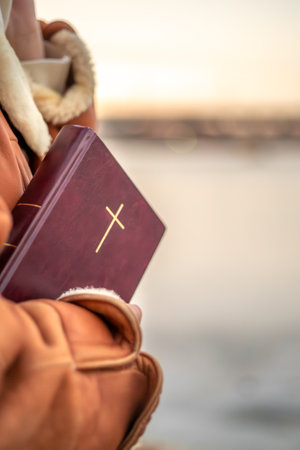 A woman holds the Bible in her hands in nature. Christianity concept.の写真素材