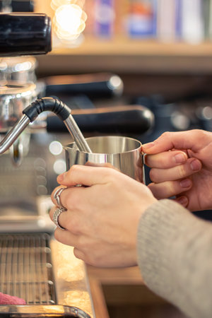 Barista steaming milk with coffee machine. Female barista making coffee in cafe.の写真素材