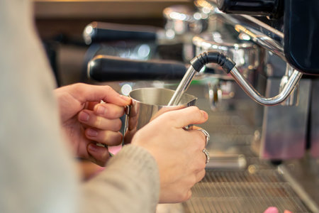 Barista steaming milk with coffee machine. Female barista making coffee in cafe.の写真素材