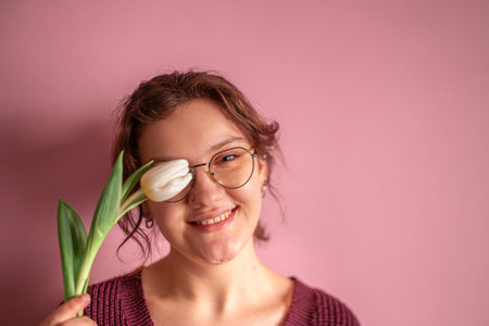 International Womens Day. Beautiful young woman with a tulip in her hand.の写真素材