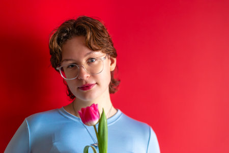 International Womens Day. Beautiful young woman with a tulip in her hand.の写真素材