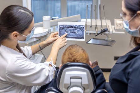 Young female dentist showing a patient a dental x-ray. Dentistry concept.の写真素材