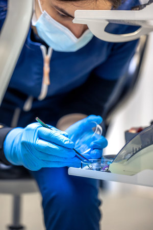 Young girl dentist choosing tools. Dentistry concept. Preparation for tooth filling.