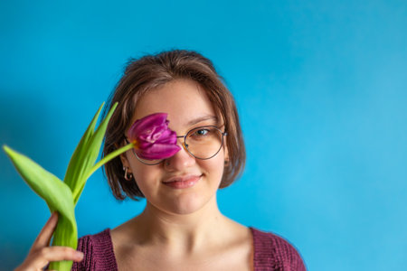 International Womens Day. Beautiful young woman with a tulip in her hand.の写真素材