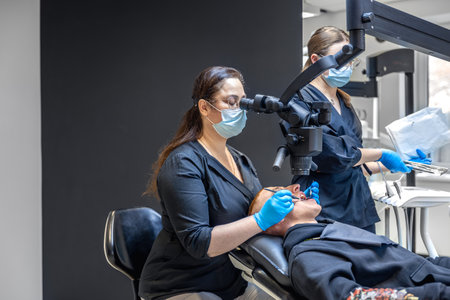 Female dentist treats patients teeth. Stomatologist working with professional equipment.の写真素材
