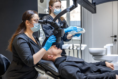 A team of dentists treats a patients teeth using modern equipment. Dentistry concept.の写真素材