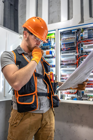 Male electrician working in electrical panel. Male electrician in overalls.の写真素材