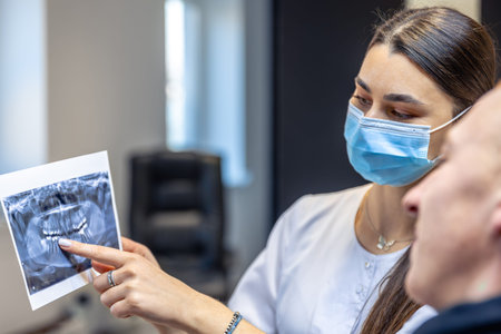 Young female dentist showing a patient a dental x-ray. Dentistry concept.