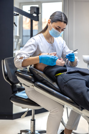 Female dentist treats patients teeth. Stomatologist working with professional equipment.の写真素材