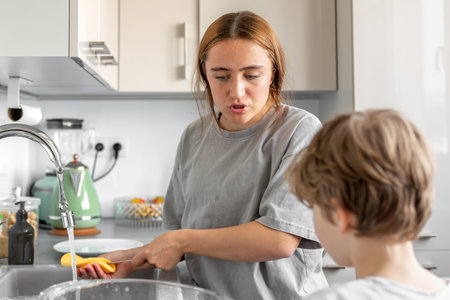 Teenage girl washing dishes. Washing dishes in the kitchen. Housework.の写真素材