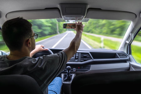 Adjusting mirror. Forest road drive. Car interior.の写真素材