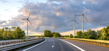 Wind turbines by highway. Eco travel. Scenic infrastructureの写真素材