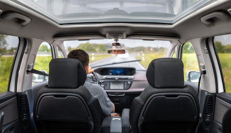 Driver on the highway. Car cabin view. Panoramic roof with rain.