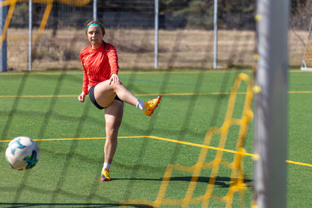 Sporty girl scores a goal into the goal. Football concept. Girl on the football field.の写真素材