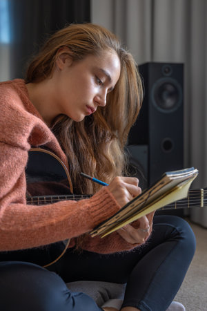 Teenage girl learning to play guitar at home. Girl composing music. Guitar.の写真素材