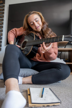 Teenage girl learning to play guitar at home. Girl composing music. Guitar.の写真素材