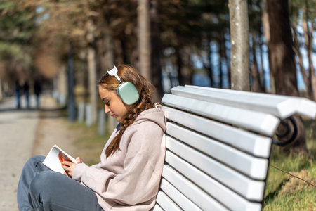 Teenage girl reading a book in the park sitting on a bench. Girl reading a book in the park.の写真素材