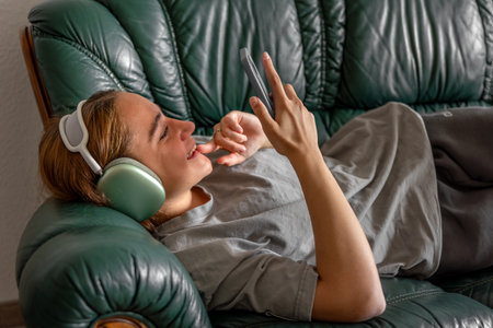 Teenage girl lying on the couch and listening to music on headphones. Listening to music.の写真素材
