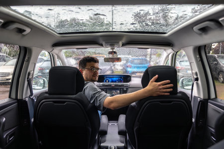 Car interior with driver. Rear seat view. Panoramic roof in the rain.の写真素材
