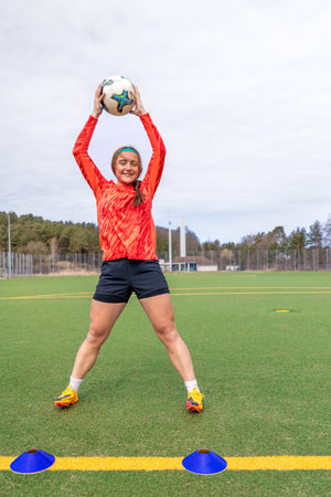 Sporty girl holding a soccer ball in her hands. Girl soccer player at soccer training. Soccer.の写真素材