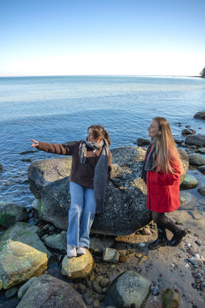 Two women walking on the seashore. Two friends enjoying and spending time together.の写真素材