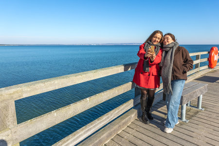 Two women on the pier. Two women walking along the pier. Sea. Ocean. Pier.の写真素材