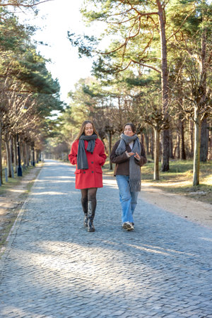 Two women walking in the park. Friends walking on a path in the park. Nature.の写真素材