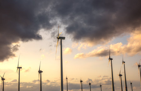 Wind turbines and dramatic clouds. Sunset sky. Renewable energy landscape.