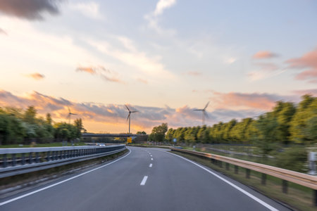 Road and wind turbines at sunset. Energy of motion. Modern nature