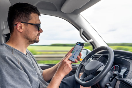 Driver using smartphone GPS. Man holding phone. Navigation in car.