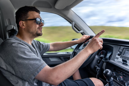 Driver pointing while driving. Man gestures in car. Reaction behind the wheel.の写真素材