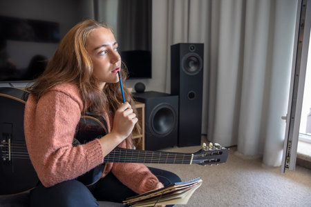 Teenage girl learning to play guitar at home. Girl composing music. Guitar.