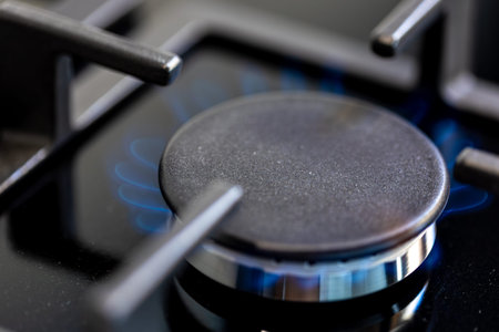 Top view gas burner. Blue flame. Glossy black stove.