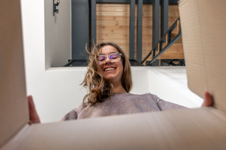 Box POV. Girl and parcel. Unboxing joyの写真素材