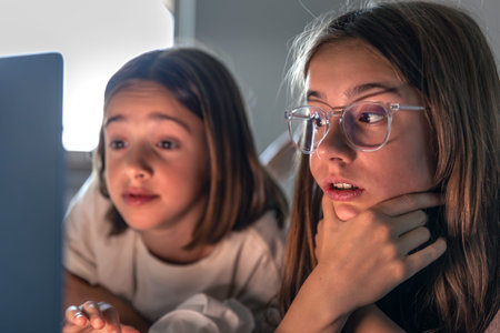 Girls looking at laptop. Focus and curiosity. Digital childhood