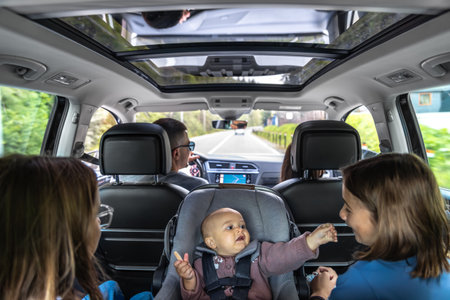 Family road trip with panoramic roof. Baby in car seat reaching sisterの写真素材