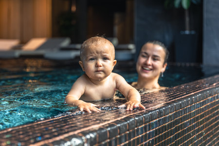 Baby holding pool edge with focused look. First self support.の写真素材