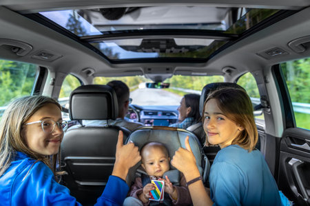 Thumbs up on the road. Kids cheering baby in car seatの写真素材