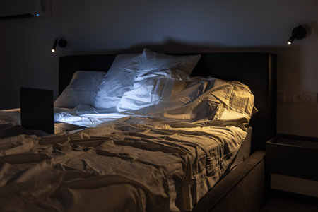 Overhead view of bed with lit laptop and contrast light. Night work.の写真素材
